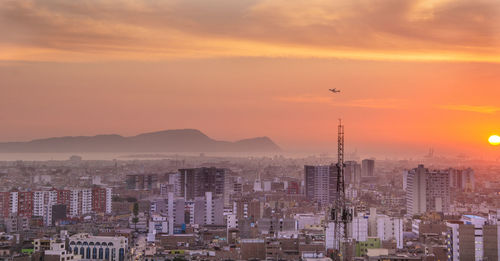 Aerial view of city against cloudy sky during sunset