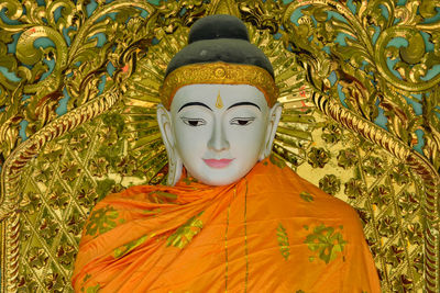Statue of buddha against orange plants