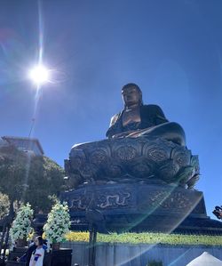 Low angle view of statue by building against sky