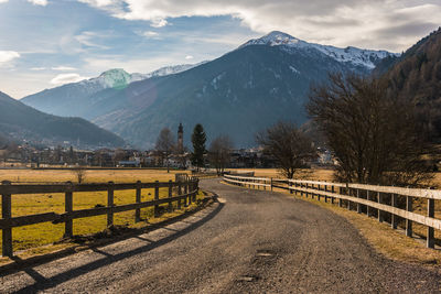 Road leading towards snowcapped mountains against sky