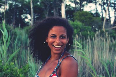 Portrait of happy woman against trees on field