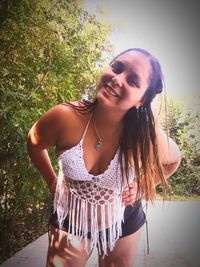 Smiling young woman standing against tree