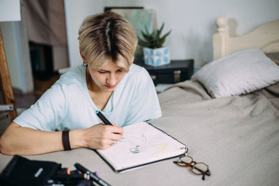 Young woman sitting on bed at home