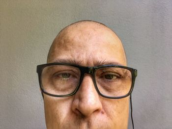 Portrait of man wearing eyeglasses against wall