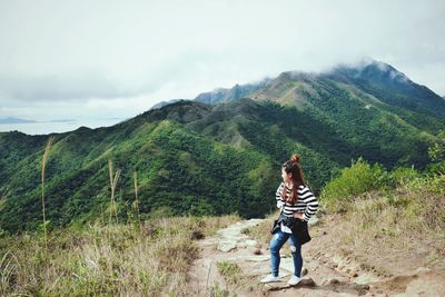 Woman standing on footpath against mountains