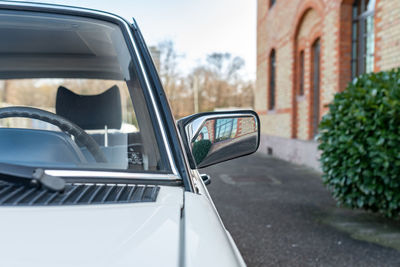 Side mirror with reflections and a brick building in the background