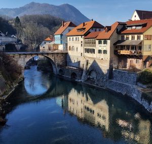 Bridge over river by houses against sky