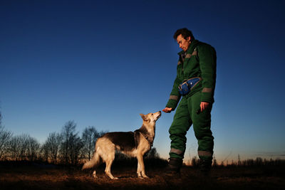 Full length of man standing with dog against sky
