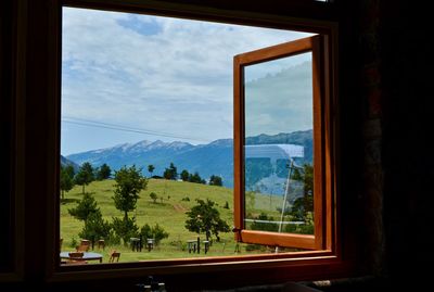 Trees and mountains seen through window