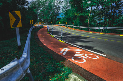 Bicycle lane sign on road amidst trees