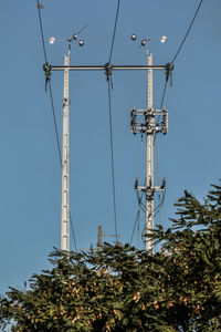 Low angle view of electricity pylons against clear sky