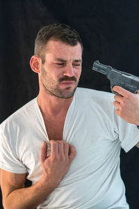 Man attempting suicide with gun against black background