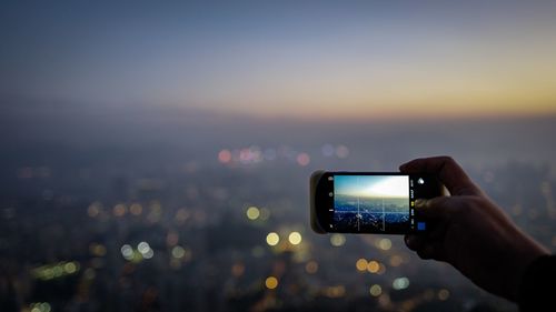 Man using mobile phone in city against sky