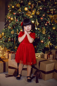 Portrait of a beautiful korean girl child in red dress at christmas with box of gifts christmas tree