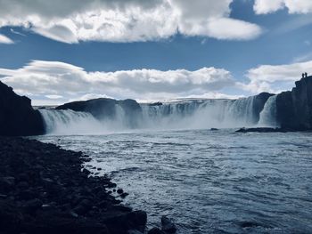 Scenic view of waterfall against sky