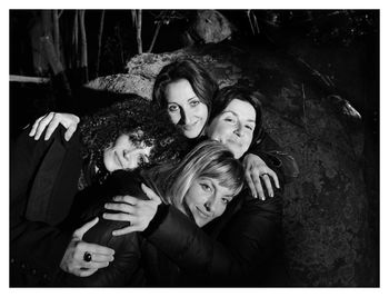 Portrait of happy friends sitting in forest at night