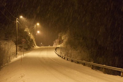 Illuminated snow covered road at night