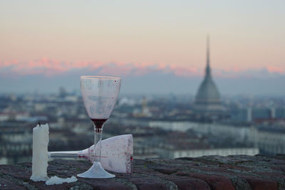 Close-up of wine glass and candle against sunrise in turin