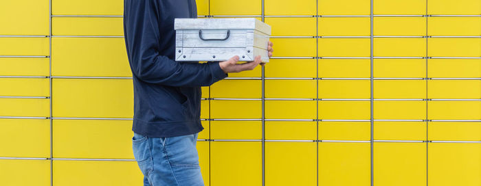 Side view of man standing against yellow wall