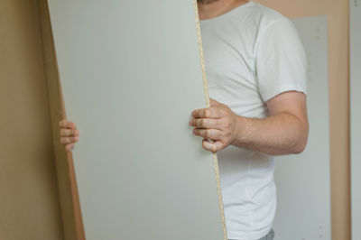 Midsection of man holding plywood at home