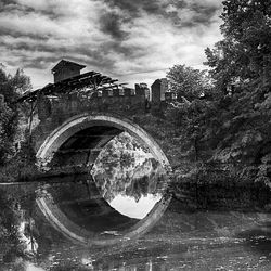 Arch bridge against cloudy sky