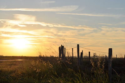 Wooden fence on field against sky during sunset