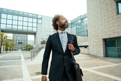 Portrait of young man standing against building