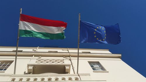 Low angle view of flag on building against blue sky