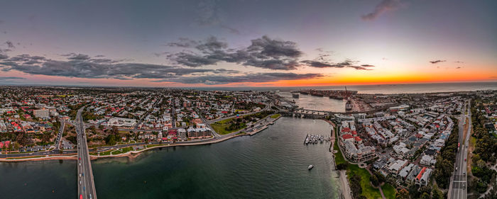 High angle view of buildings by sea against sky during sunset