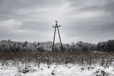 Electricity pylon on field against sky during winter