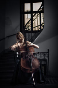 Young woman playing cello at home