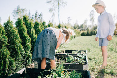 Siblings looking at their homegrown vegetable patch in the yard