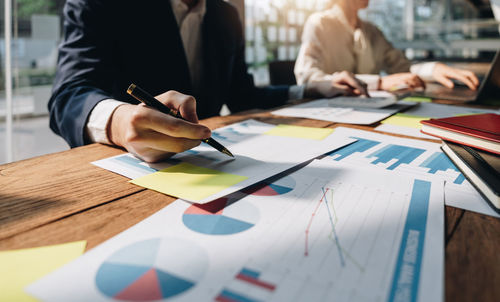 Midsection of business colleagues working on table