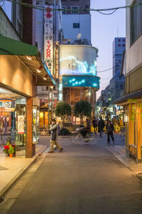 People walking on road against buildings in city