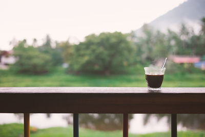 Black coffee on railing against trees