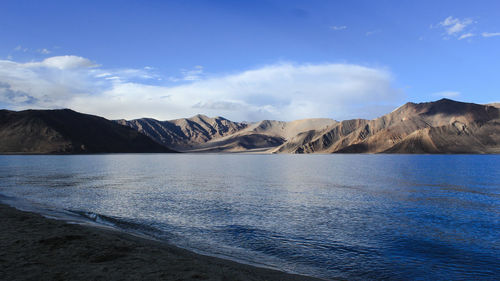 Scenic view of sea and mountains against blue sky