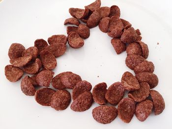 High angle view of heart shaped chocolate corn flakes against white background