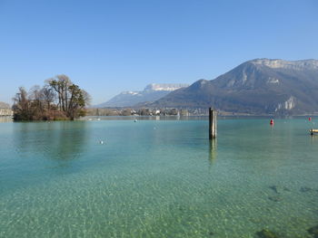 Scenic view of sea and mountains against clear blue sky