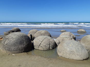 Rocks on beach against clear sky