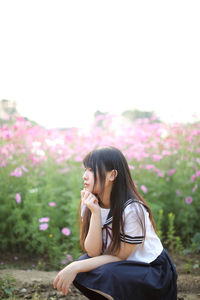 Young woman sitting on pink flowering plant