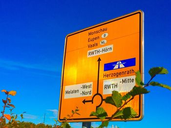 Low angle view of information sign against clear blue sky