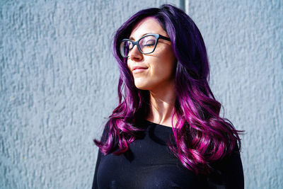 Portrait of smiling woman standing against wall