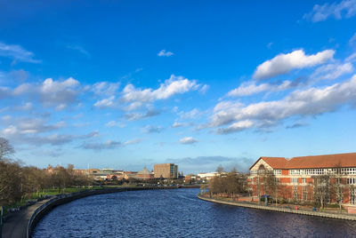 River amidst buildings in city against sky