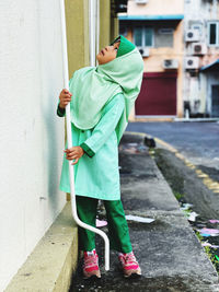 Side view of man holding umbrella standing against wall