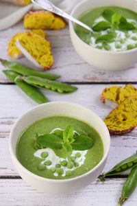 Chilled soup puree of green peas, seasoned with green onion, mint and crunchy toasted  rusk bread