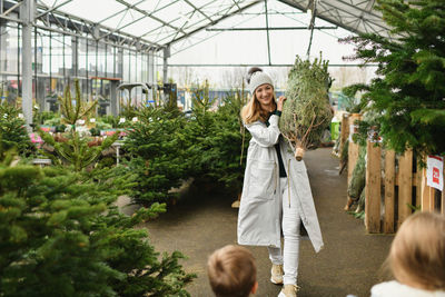 Mother and kids buying a christmas tree in the market.