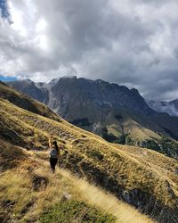 Rear view of man hiking on mountain against sky