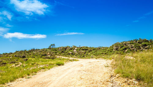 Road along countryside landscape against blue sky