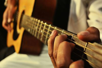 Midsection of man playing guitar