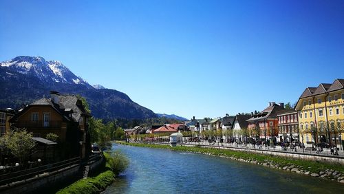 River amidst houses and buildings against clear blue sky